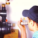 man installing a pump to help reduce moisture in basement