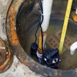sump pump in a sump pit being measured by a plumber